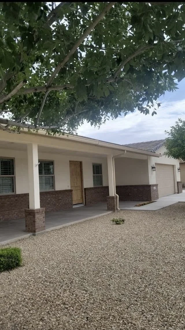 Peoria, Arizona ranch home with freshly painted cream stucco, brick wainscot, and white porch posts and fascia