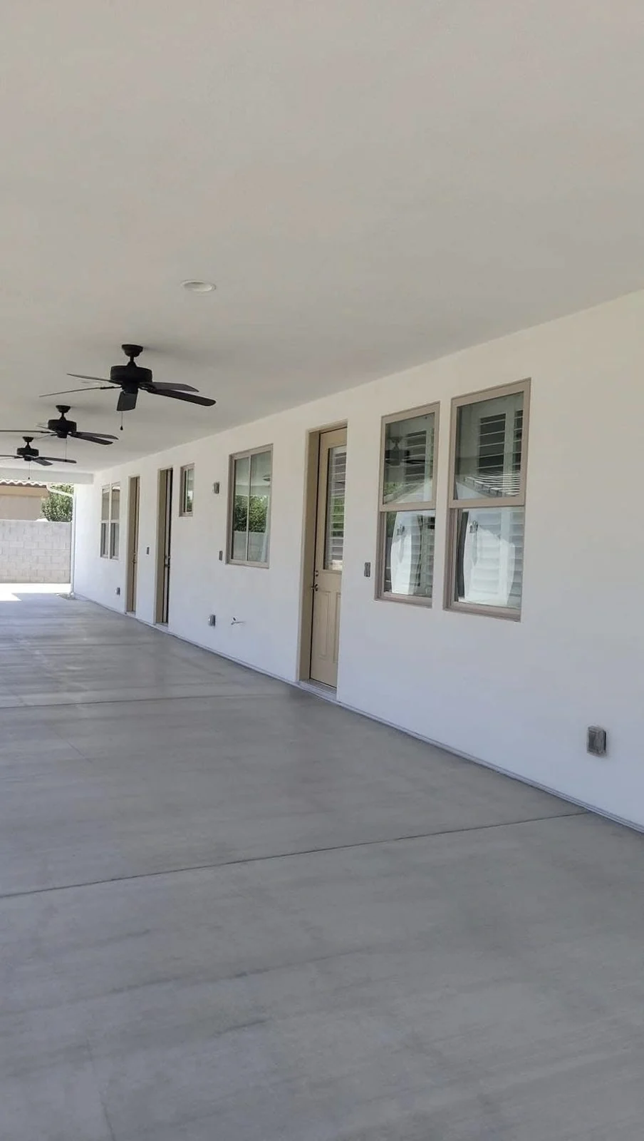Finished covered patio in Peoria, Arizona with a freshly painted white ceiling, black ceiling fans and a gray concrete floor